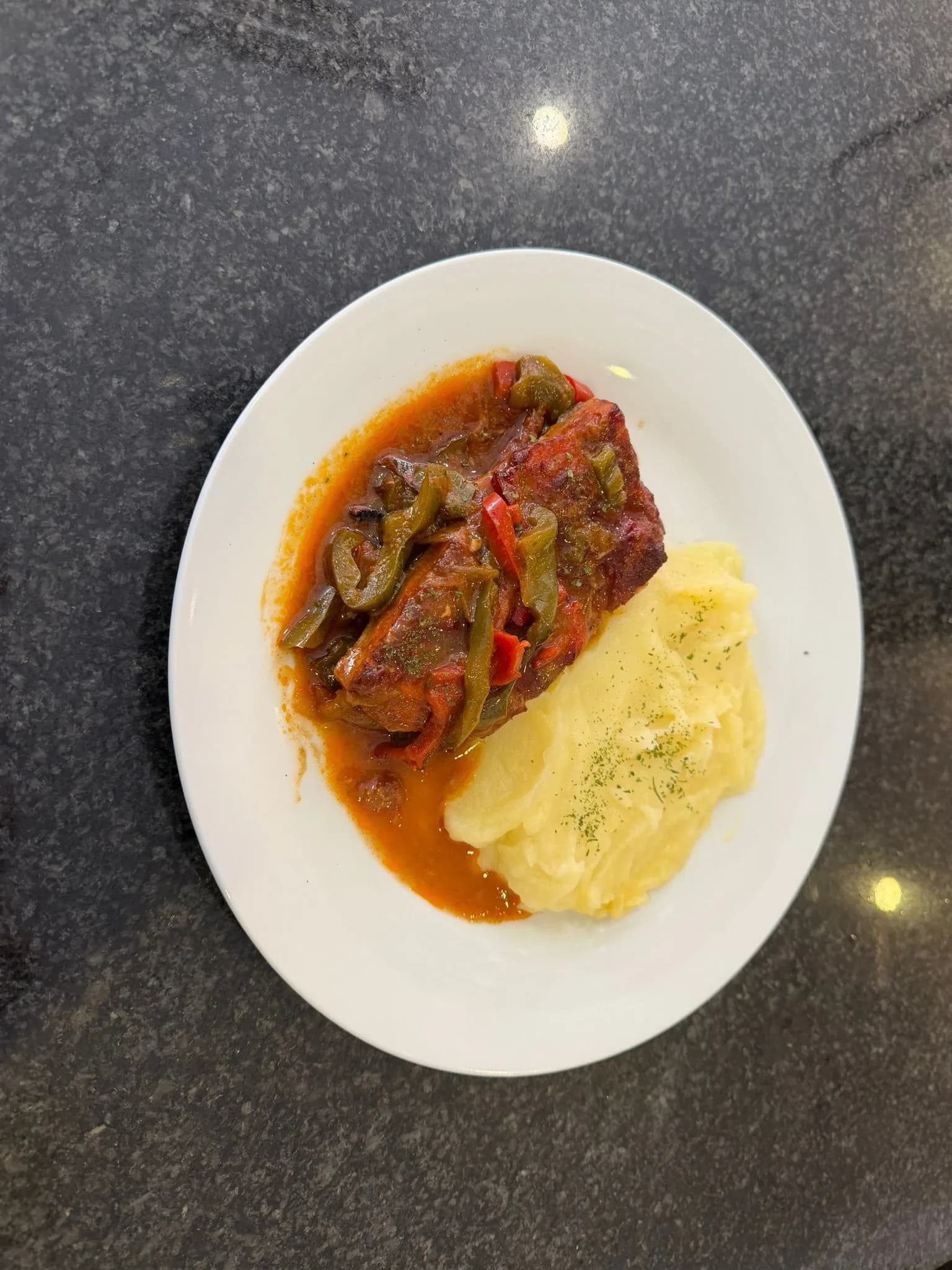 Costilla guisada en salsa con pimientos acompañada de puré de patata