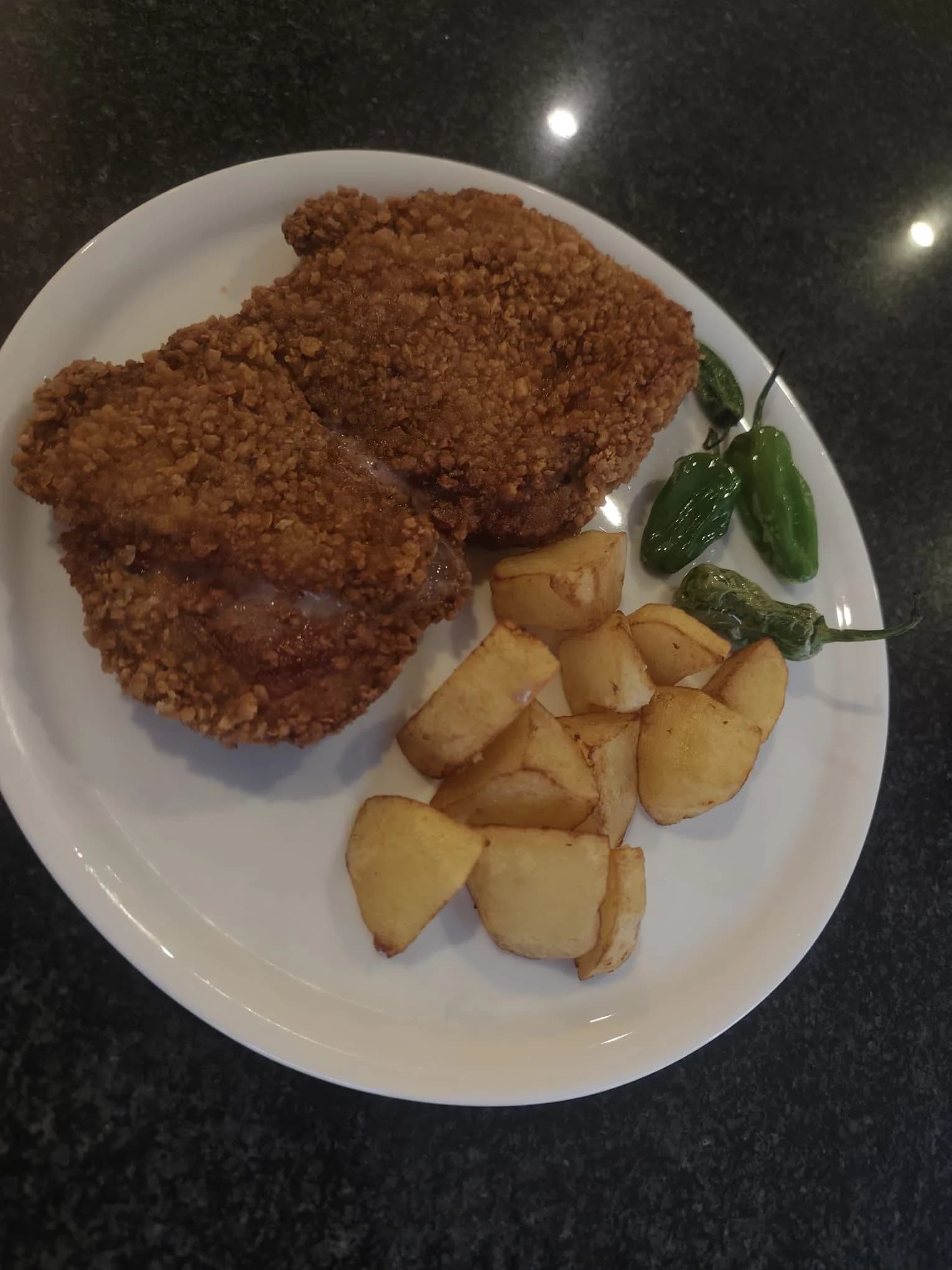 Filete empanado crujiente con patatas fritas caseras y pimientos de Padrón
