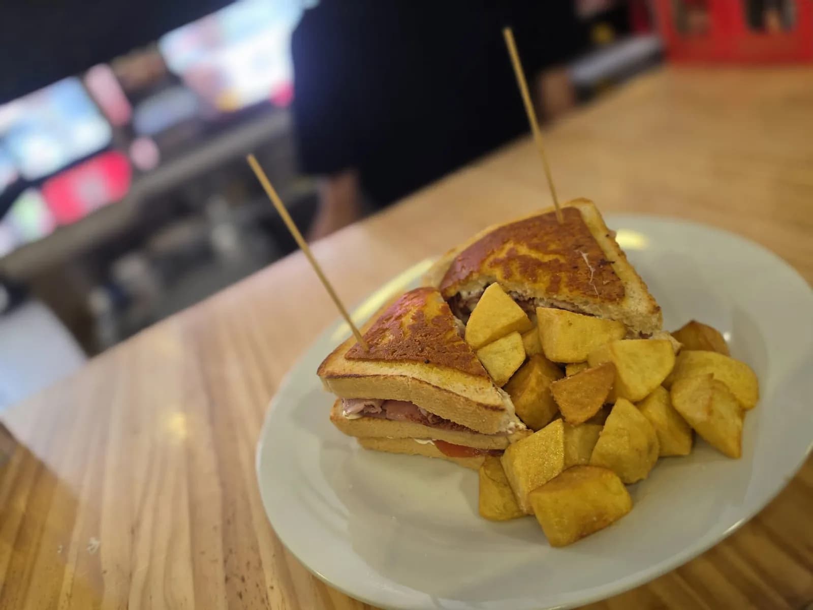 Sándwich a la plancha cortado en triángulos con brochetas y patatas fritas caseras